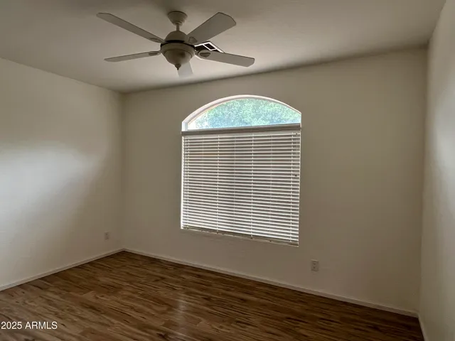 a view of an empty room with a window and wooden floor