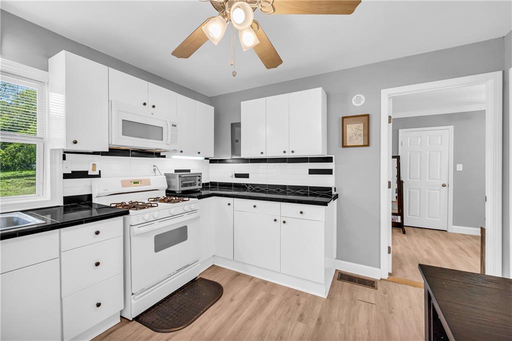 3351 Phillip Circle Decatur, GA 30032 - Photo 7 of 29 a kitchen with stainless steel appliances granite countertop white cabinets a sink a stove a dining table and chairs with wooden floor