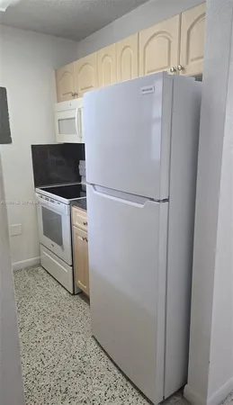 a white refrigerator freezer and a stove sitting inside of a kitchen