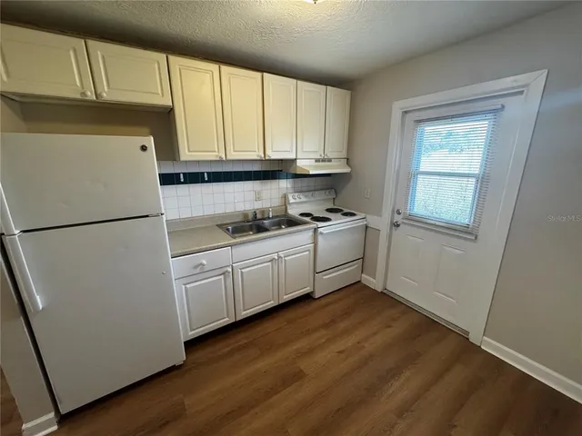 a kitchen with granite countertop white cabinets and white appliances