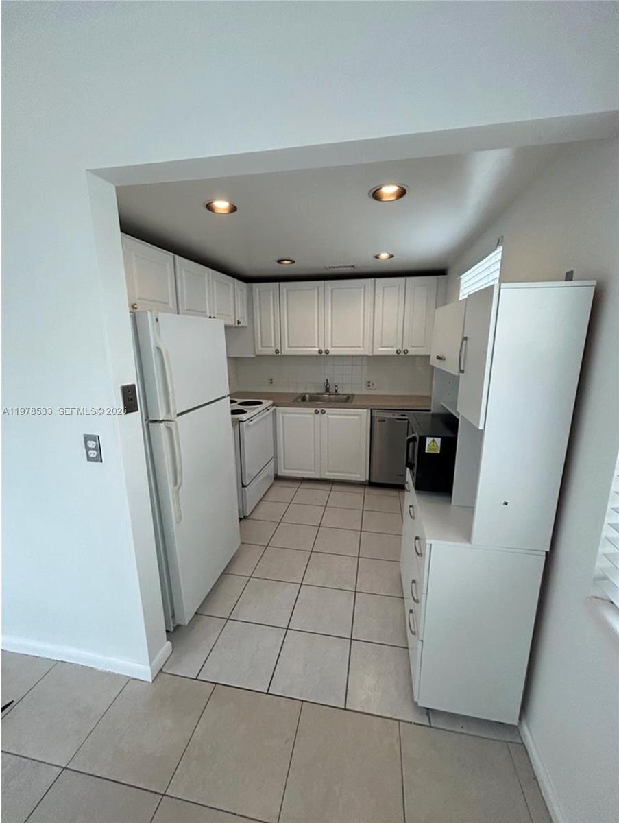 550 Mansfield M, Unit 550 Boca Raton, FL 33434 - Photo 6 of 30 a kitchen with a refrigerator and white cabinets