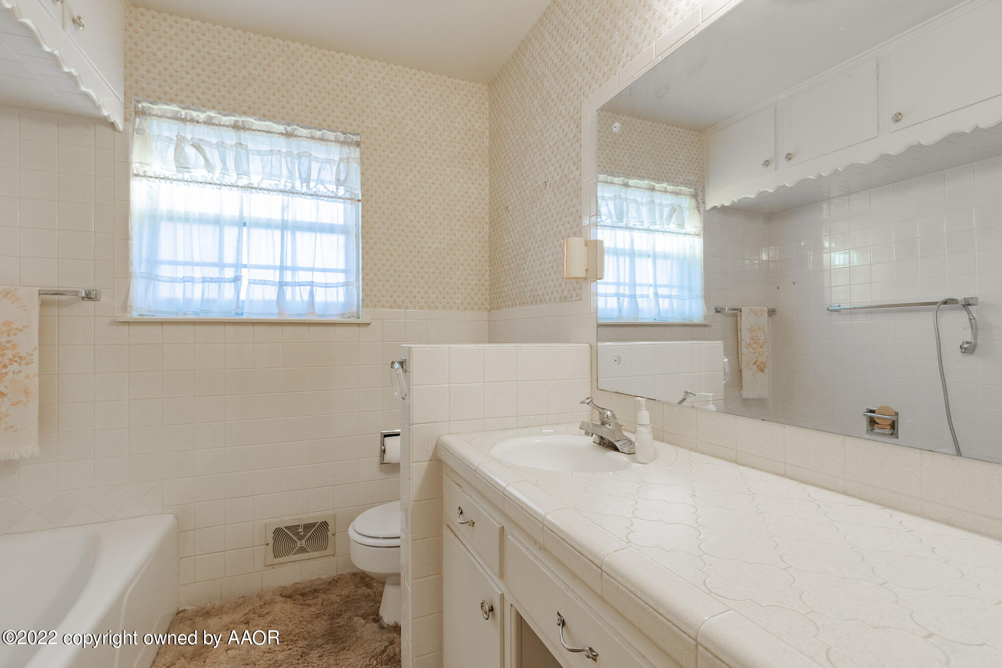 6013 Calumet Road Amarillo, TX 79106 - Photo 13 of 26 a bathroom with a granite countertop toilet a sink a mirror and a window