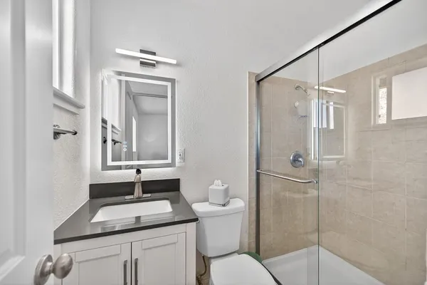 a bathroom with a granite countertop sink toilet and shower