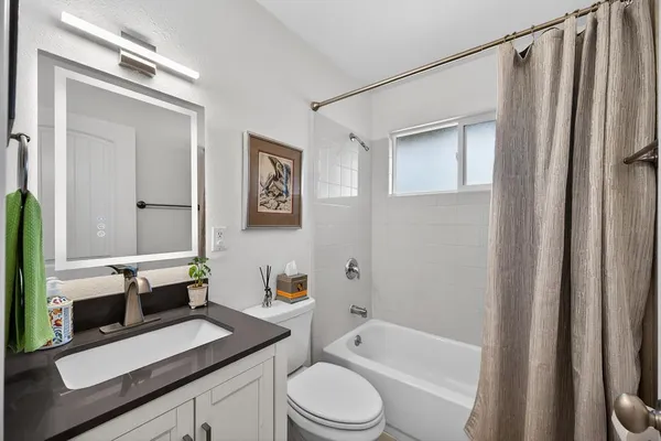 a bathroom with a sink a toilet a mirror and shower