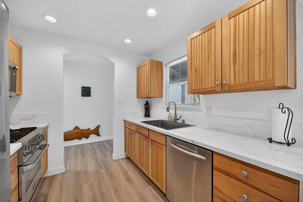 a kitchen with granite countertop a sink dishwasher stove and cabinets