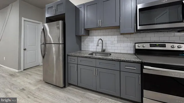 a kitchen with granite countertop a refrigerator stove and microwave