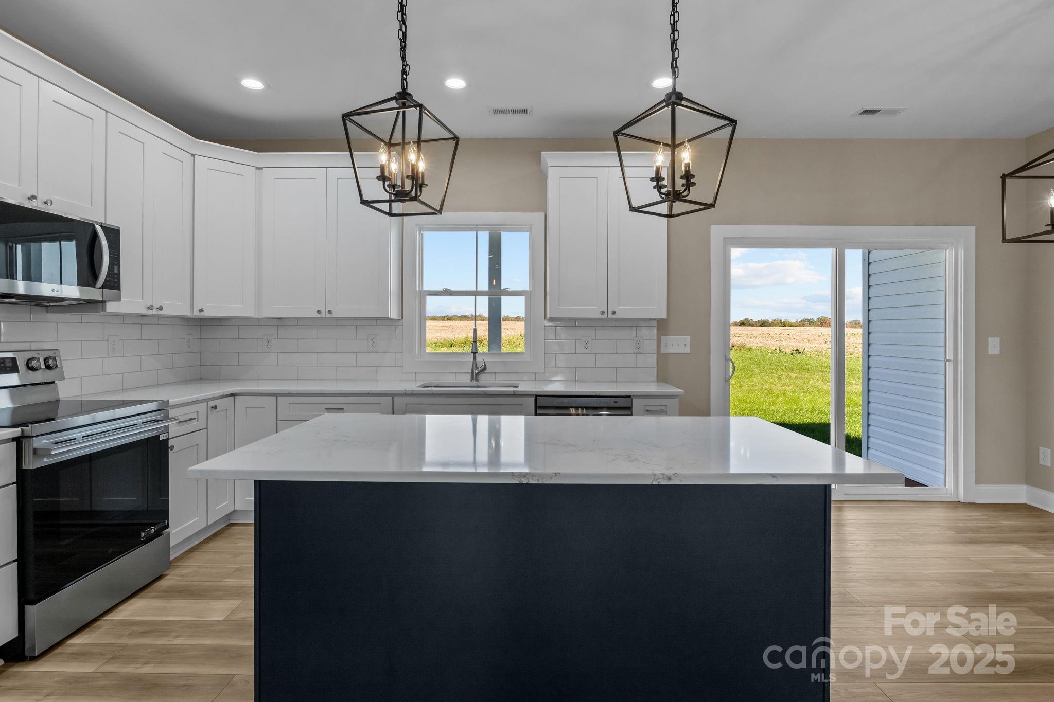 1716 Jennings Road Olin, NC 28660 - Photo 17 of 48 a kitchen with kitchen island granite countertop a stove a sink a window and wooden floor