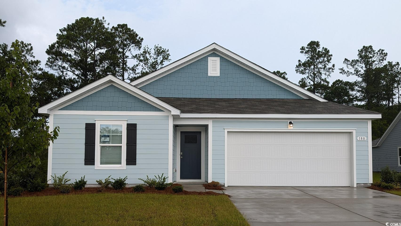 View of front facade featuring a shingled roof, driveway, an attached garage, and a front yard