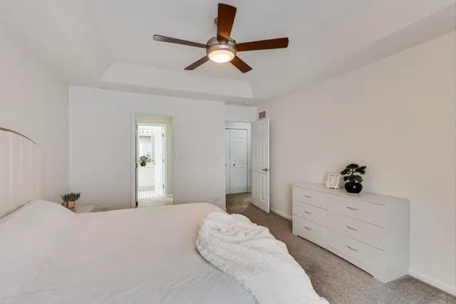 a bedroom with a large bed and a chandelier fan