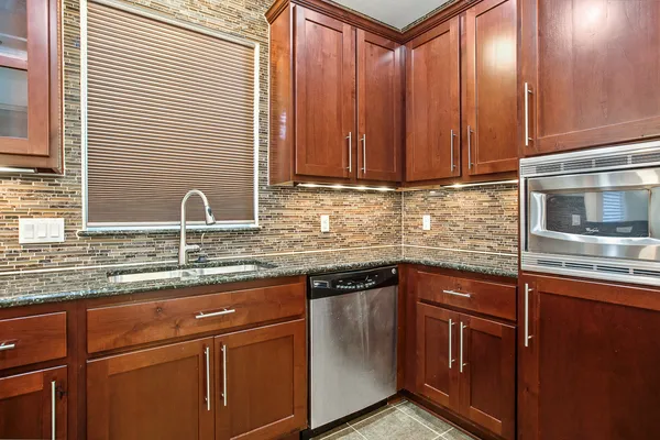 a kitchen with stainless steel appliances granite countertop wooden cabinets a sink and dishwasher