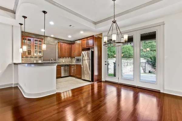 a kitchen with stainless steel appliances granite countertop a refrigerator a sink dishwasher a stove and a dining table with wooden floor