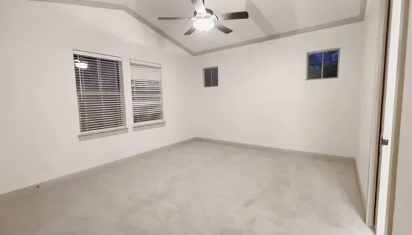en empty room with windows and ceiling fan