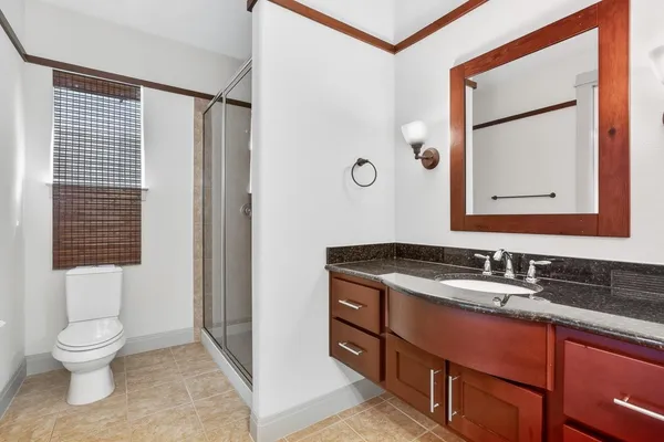 a bathroom with a granite countertop sink toilet a mirror and shower