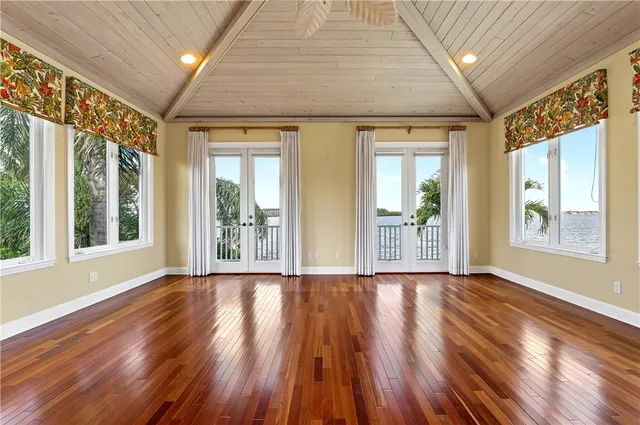 a view of an empty room with wooden floor and a kitchen