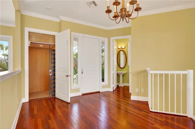 an empty room with windows and chandelier fan