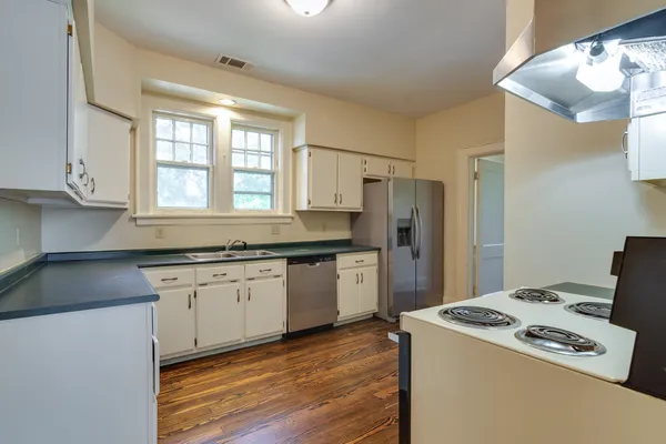 a kitchen with granite countertop a sink a refrigerator a stove and white cabinets