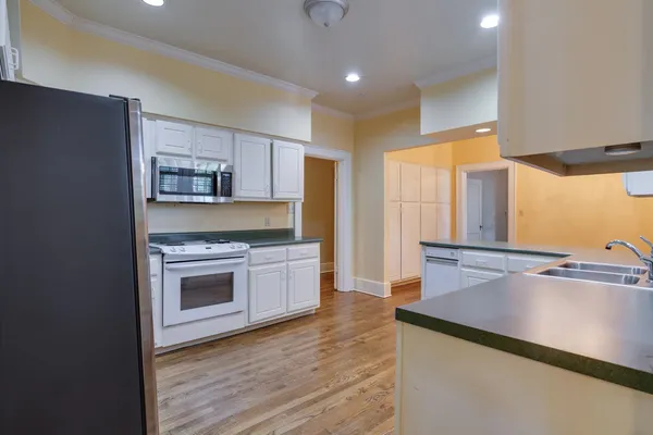 a kitchen with stainless steel appliances a sink cabinets and wooden floor