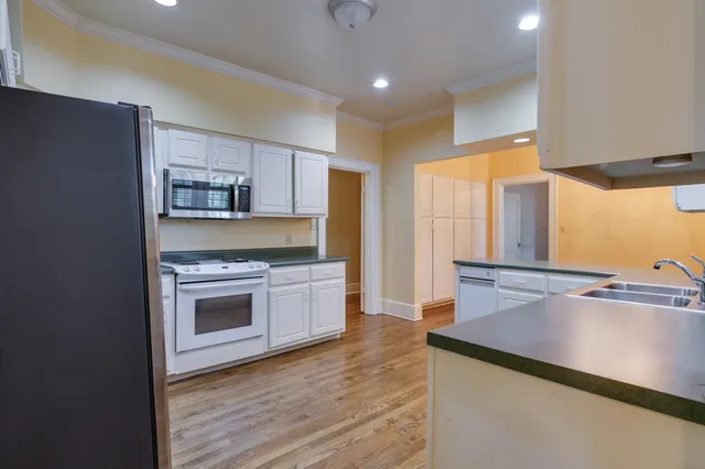 a kitchen with stainless steel appliances a sink cabinets and wooden floor
