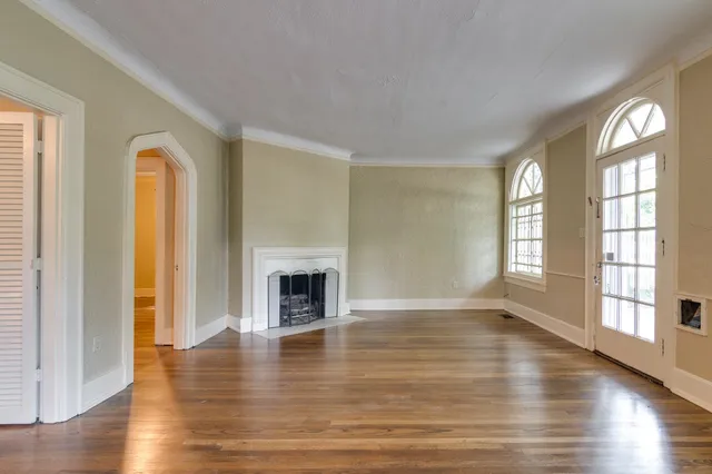 a view of an empty room with window and wooden floor