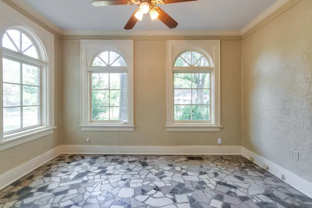 an empty room with windows and chandelier fan