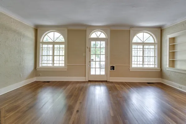 a view of an empty room with wooden floor and a window