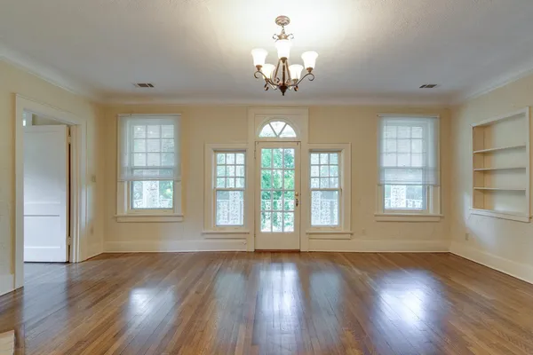 a view of an empty room with wooden floor and a window