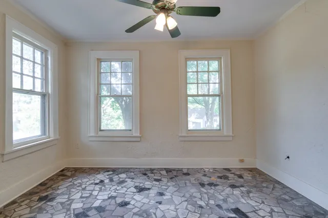 an empty room with windows and fan