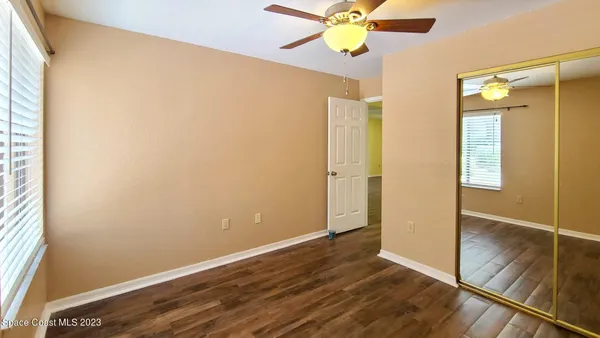 an empty room with wooden floor fan and windows