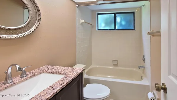 a bathroom with a granite countertop sink a mirror and a bathtub