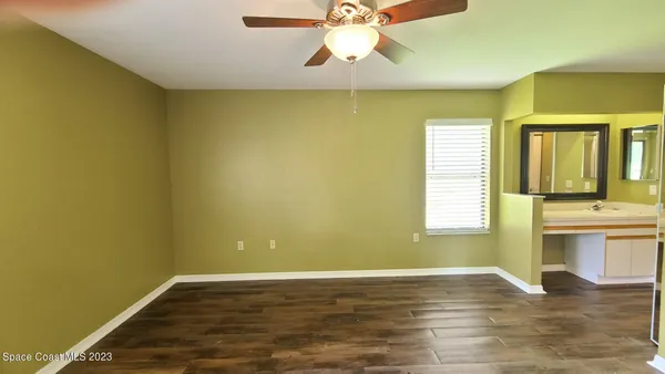 a view of an empty room with window and wooden floor