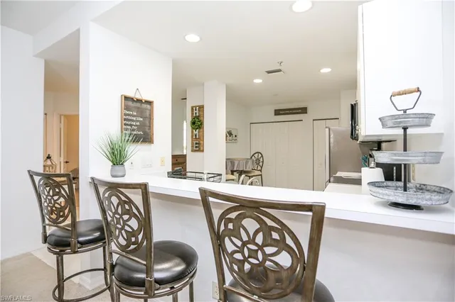 a kitchen with stainless steel appliances a dining table chairs and a refrigerator
