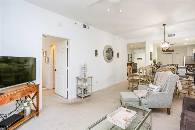 a living room with furniture a flat screen tv and kitchen view