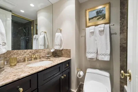 a bathroom with a granite countertop sink mirror vanity and toilet