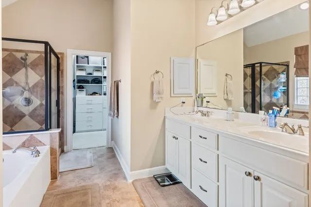 a spacious bathroom with a double vanity sink a mirror a shower and a bathtub