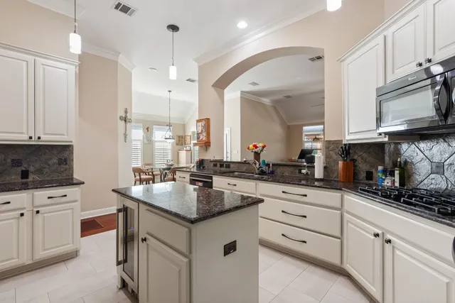 a kitchen with granite countertop a sink stainless steel appliances and white cabinets