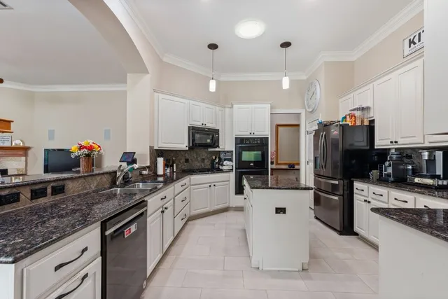 a large white kitchen with stainless steel appliances kitchen island granite countertop a stove refrigerator and cabinets