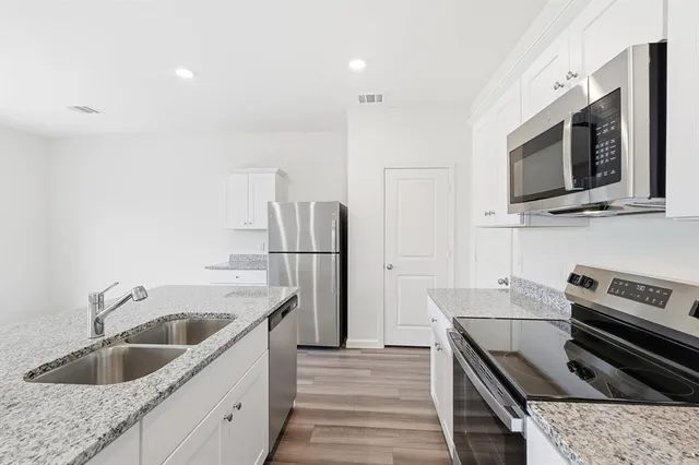 a kitchen with granite countertop kitchen island stainless steel appliances a sink stove and refrigerator