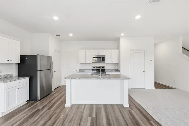 a kitchen with stainless steel appliances granite countertop a sink stove and refrigerator