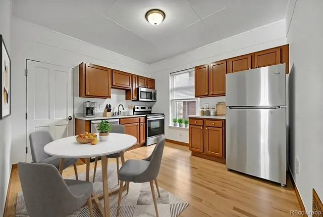 a kitchen with stainless steel appliances granite countertop a refrigerator a stove top oven a sink dishwasher and white cabinets with wooden floor