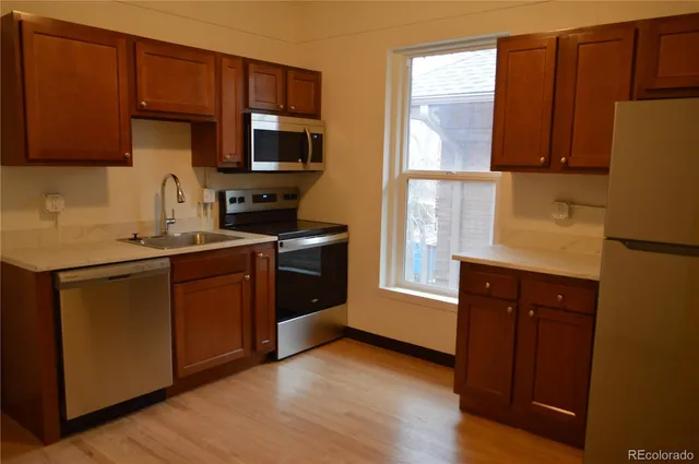 a kitchen with stainless steel appliances granite countertop wooden cabinets a stove a sink and a refrigerator