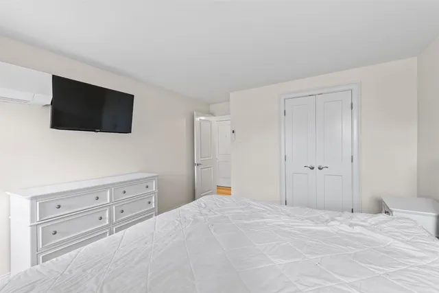 a bedroom with a bed and a flat screen tv in white walls