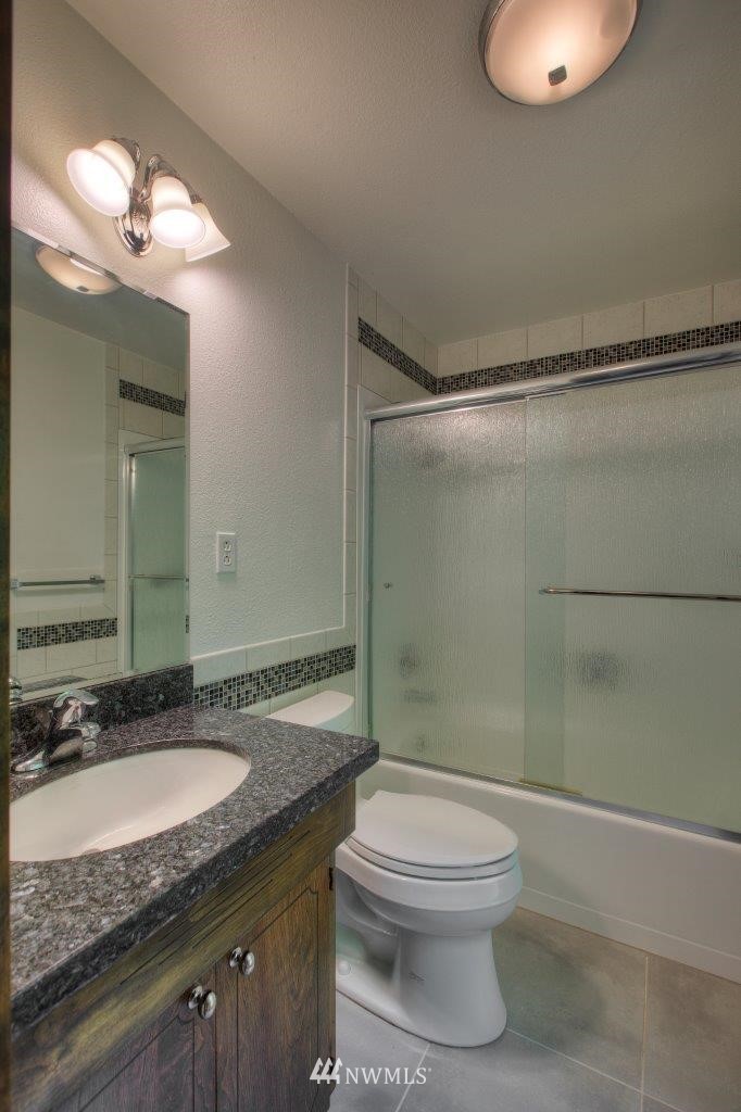 22004 Southeast Bain Road Renton, WA 98058 - Photo 12 of 27 a bathroom with a granite countertop sink toilet a mirror and shower