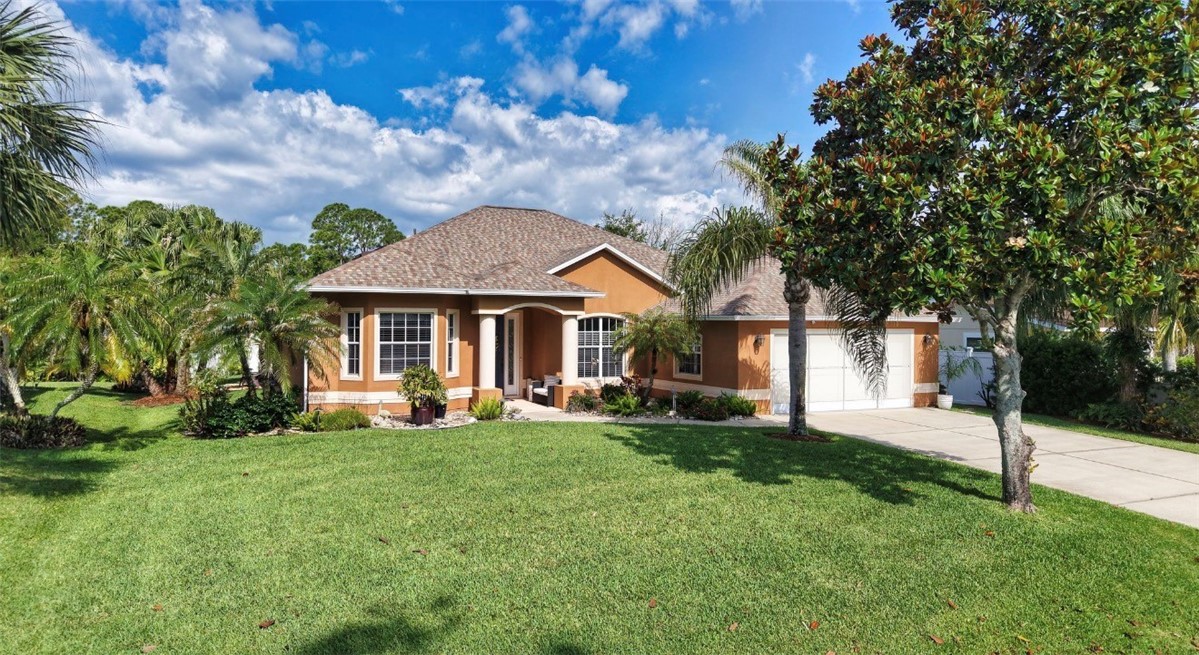 1771 Mistletoe Street Sebastian, FL 32958 - Photo 3 of 36 a front view of a house with a garden and trees