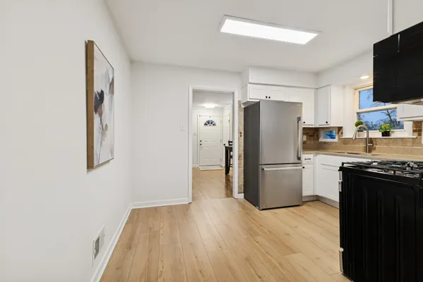 a kitchen with a refrigerator a stove top oven a sink and dishwasher with wooden floor