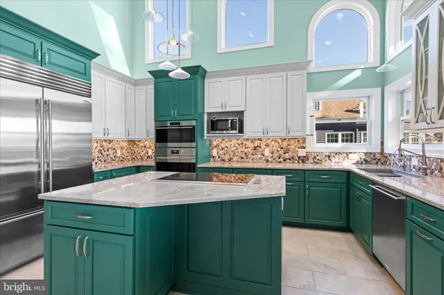 a kitchen with kitchen island granite countertop a sink cabinets and stainless steel appliances