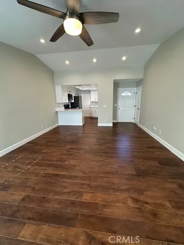 a kitchen with stainless steel appliances kitchen island granite countertop a stove top oven a sink dishwasher and white cabinets with wooden floor