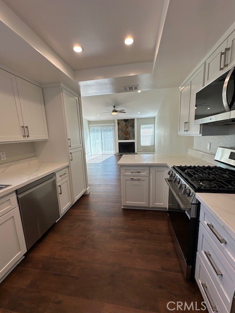 44649 La Paz Road, Unit F Temecula, CA 92592 - Photo 5 of 23 a kitchen with stainless steel appliances kitchen island granite countertop a stove top oven a sink dishwasher and white cabinets with wooden floor