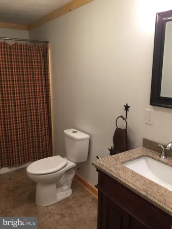 a bathroom with a granite countertop toilet and sink
