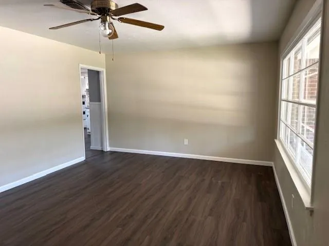 an empty room with wooden floor fan and windows