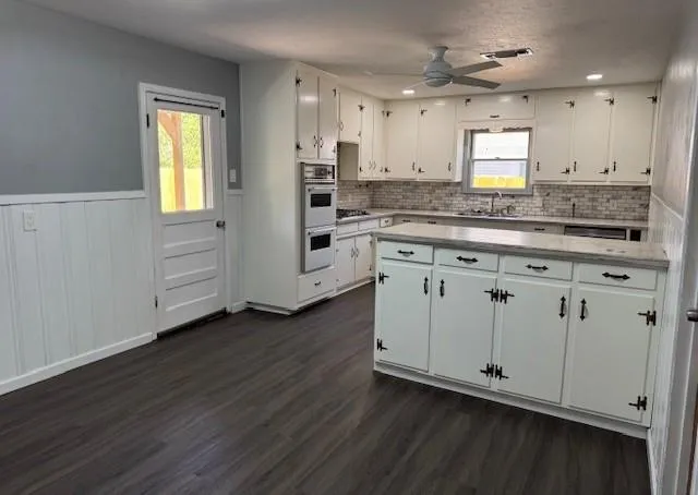a kitchen with white cabinets and sink